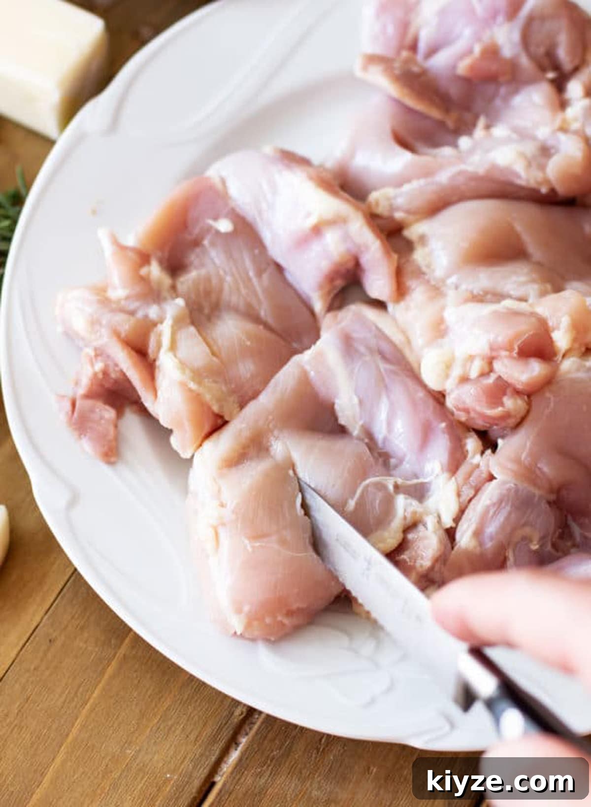 Person cutting a slit in raw chicken thighs in preparation for marinade.
