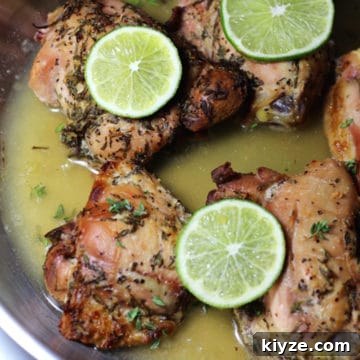 Silver pan containing 5 Lemon Thyme Chicken thights with Garlic and Rosemary, topped with lime slices.