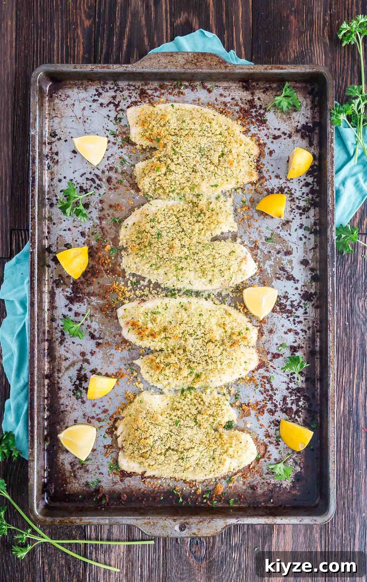 Crispy Parmesan-Crusted Fish Fillets Recipe 8 An overhead image of a pan of crusted fish and lemon wedges.