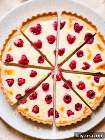 raspberry mascarpone tart cut into 8 slices on a large plate.