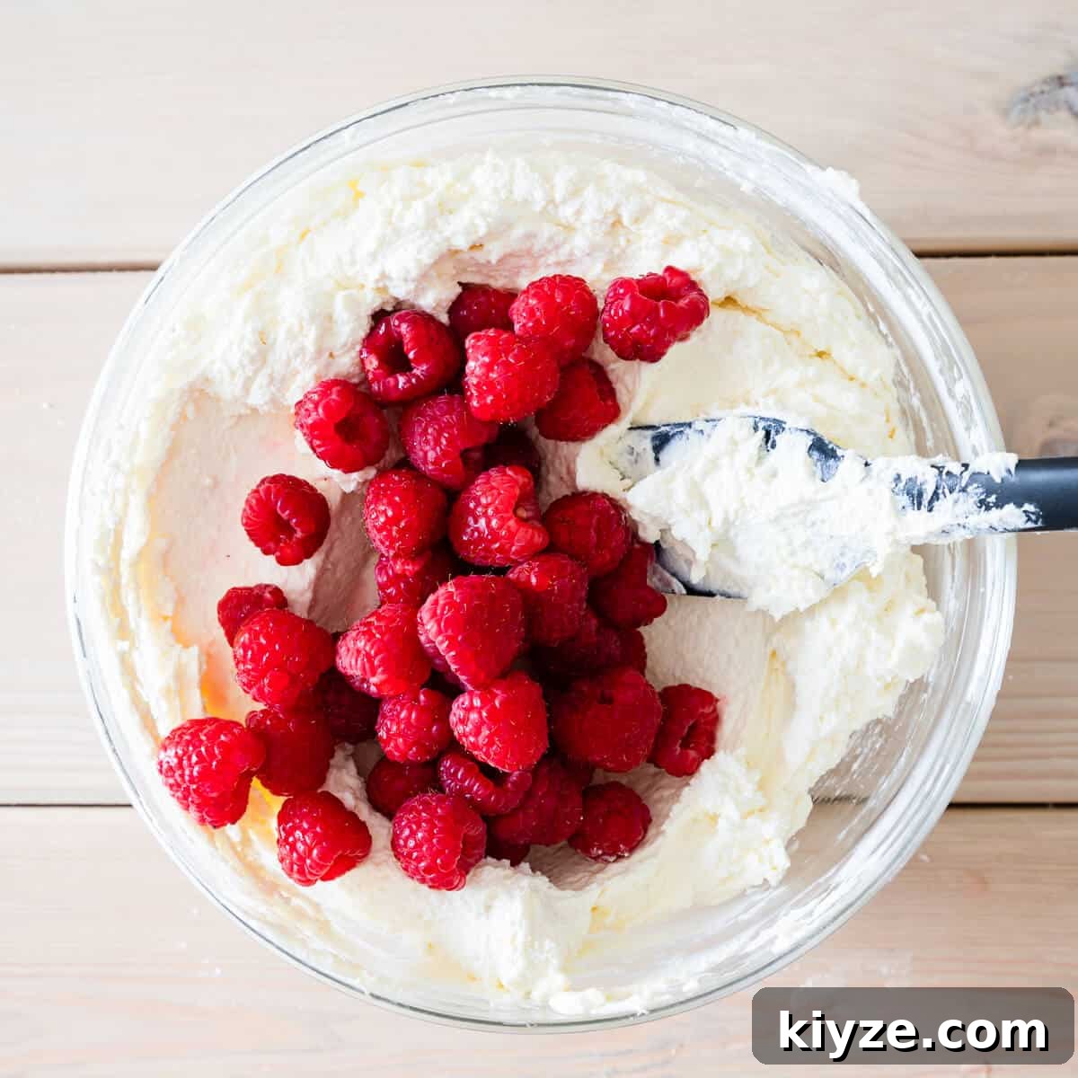 No-Bake Raspberry and White Chocolate Cheesecake Recipe 6 mixing bowl with cheesecake filling and fresh raspberries.