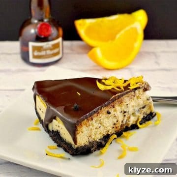 grand marnier cheesecake on white plate with slices of orange and mini bottle of grand marnier in the background