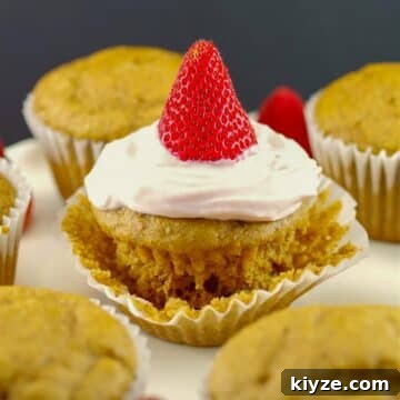 Pancake cupcake with Greek yogurt and strawberry topping, on loosened muffin liner wrapper, with other cupcake pancakes around it