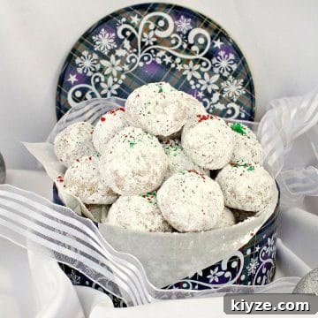Almond Snowball cookies in a blue Christmas cookie tin, with ribbon around it