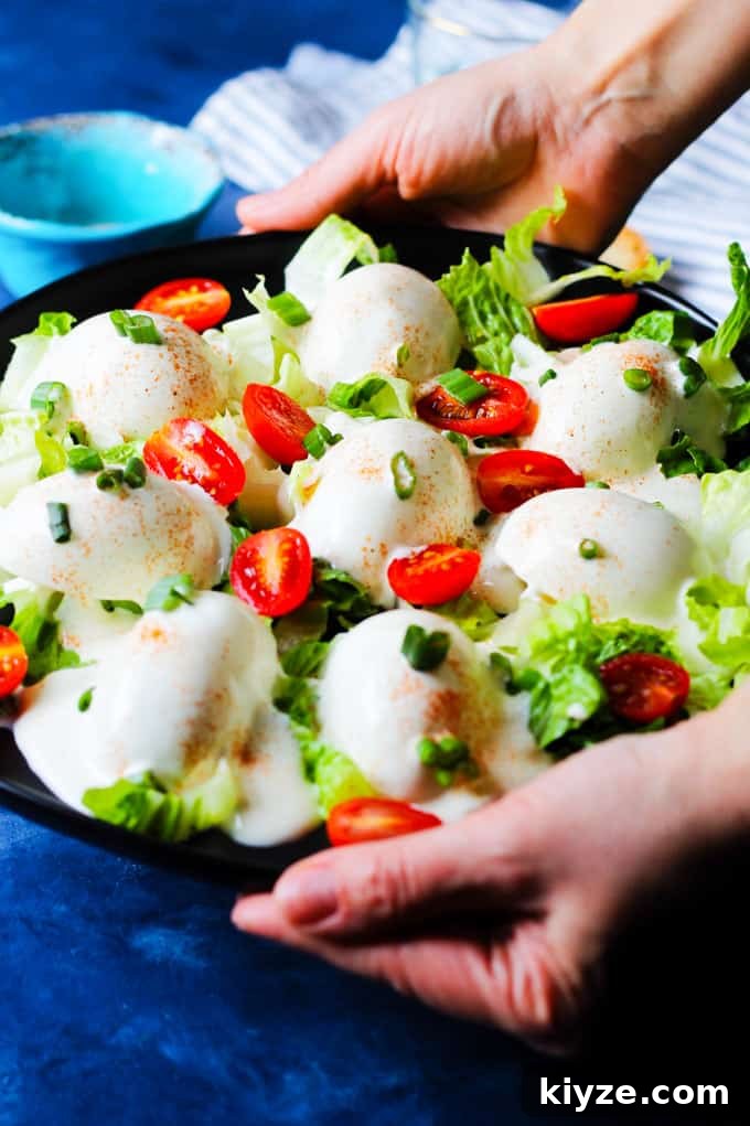 Polish Deviled Eggs with Classic Mayonnaise Filling 2 Serving Eggs Mayonnaise on a black serving plate with scallions and cherry tomatoes