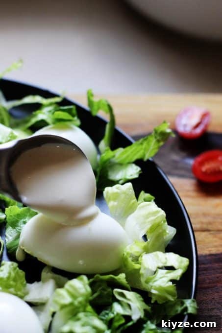 Spooning over mayonnaise sauce on the eggs