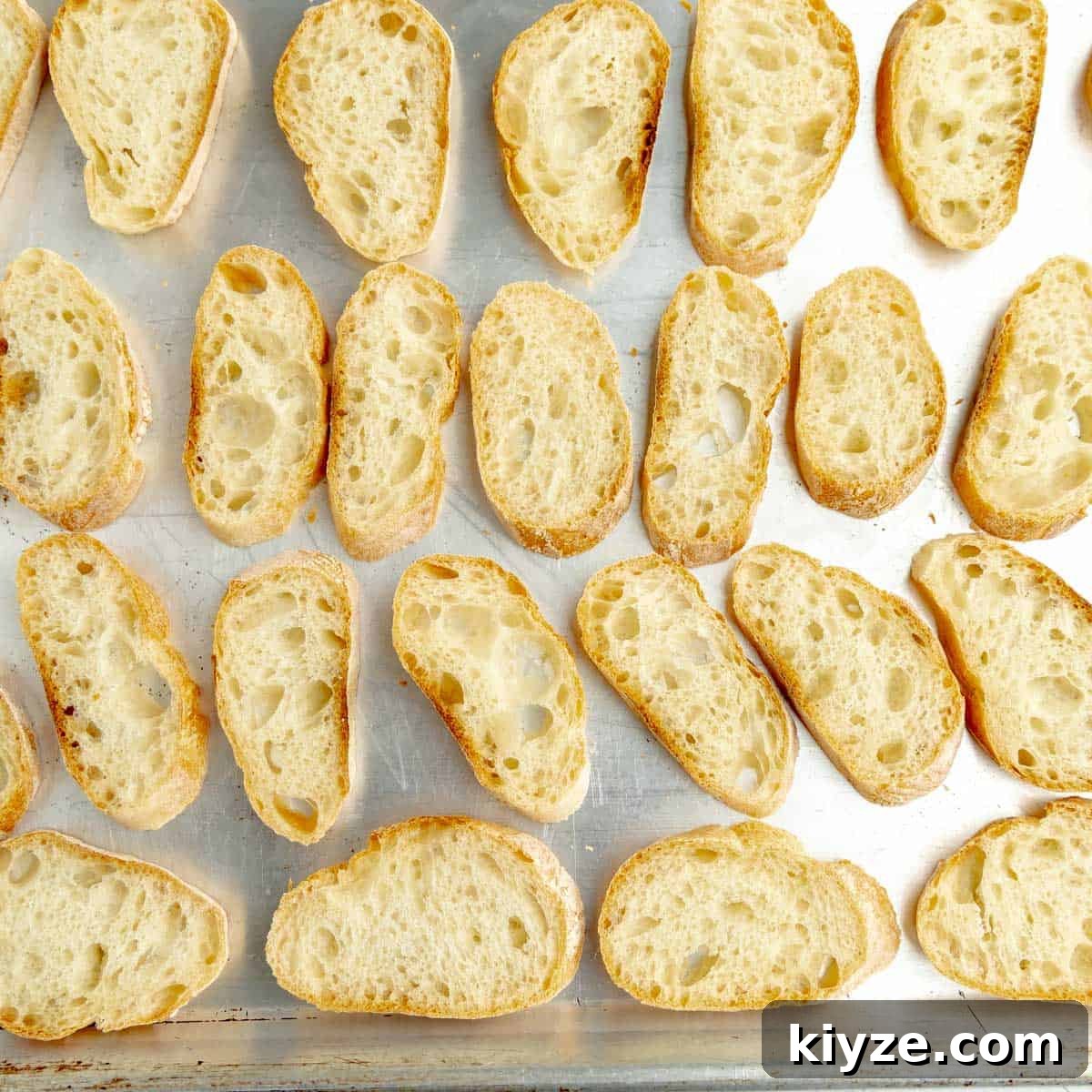 Crispy Garlic Crostini with Olive Oil and Herbs 5 Slices of baguette lying on a sheet pan