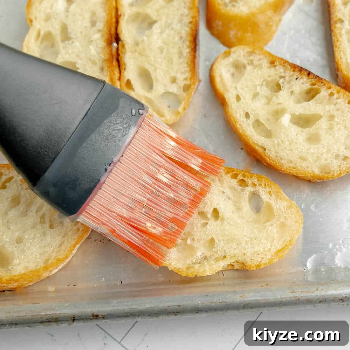Crispy Garlic Crostini with Olive Oil and Herbs 6 A pastry brush brushing olive oil on the toasts.