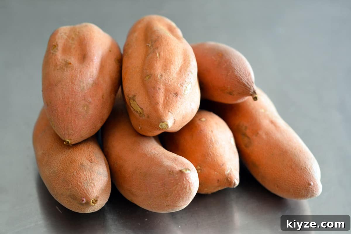 Crispy Sweet Potato Fries: Oven or Air Fryer Method 4 A pile of garnet yams or red fleshed sweet potatoes on a stainless steel counter.