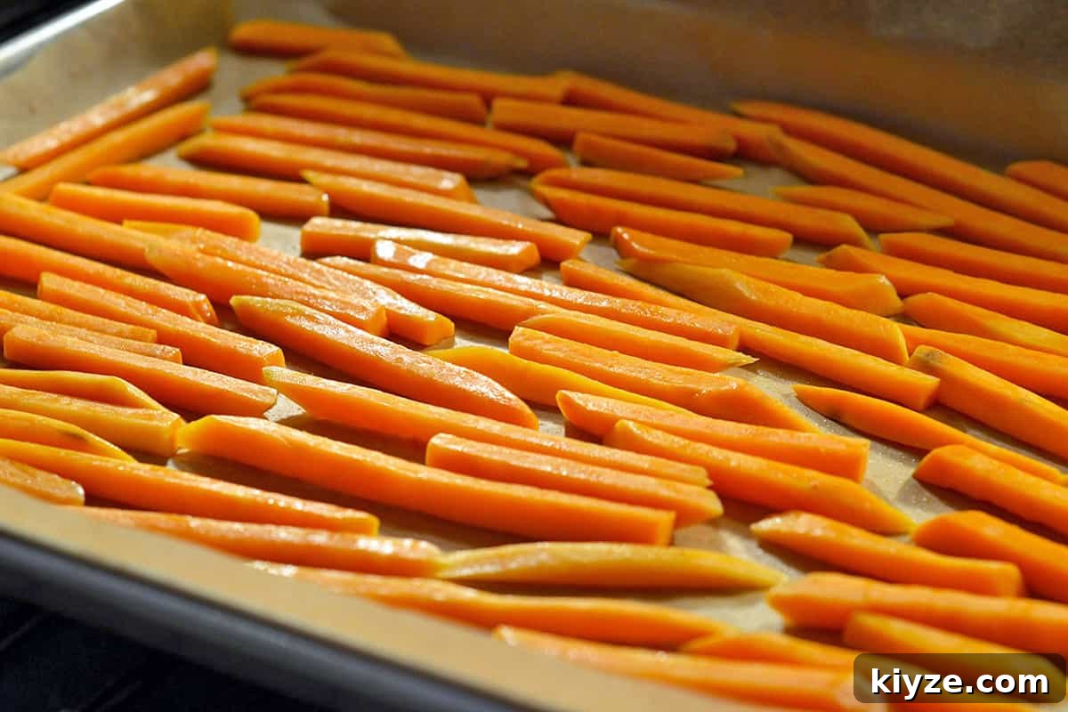 Crispy Sweet Potato Fries: Oven or Air Fryer Method 6 Sweet potato fries are in a single layer in a parchment lined rimmed baking sheet about to be baked in the oven.