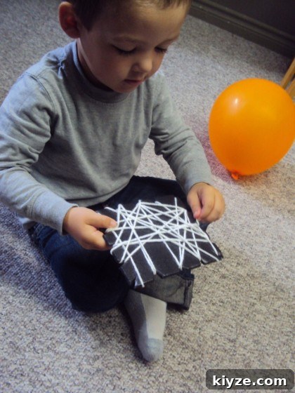 Spider and Web Craft Activities to Boost Preschool Fine Motor Skills 5 Toddler weaving yarn around a styrofoam produce tray