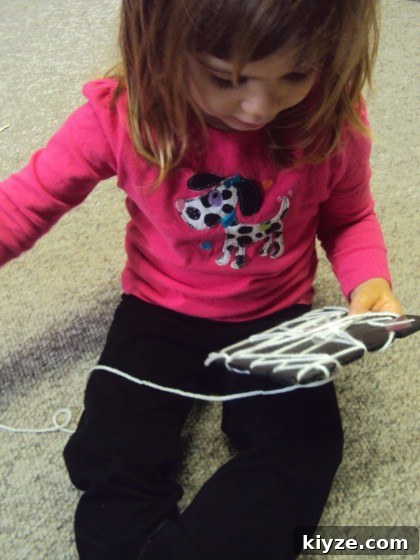 Spider and Web Craft Activities to Boost Preschool Fine Motor Skills 6 toddler weaving a spiders web with yarn