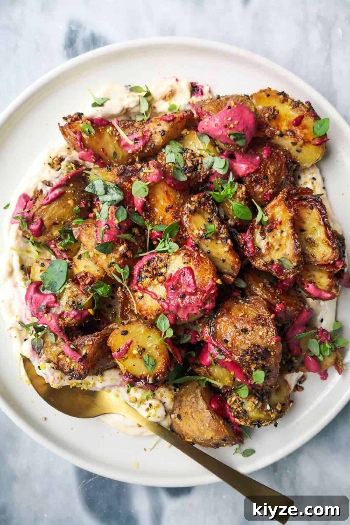 Crispy Dukkah Potatoes with Aioli & Pink Tahini Drizzle 2 Crispy dukkah potatoes on a bed of aioli with thyme and pink tahini scattered on top.