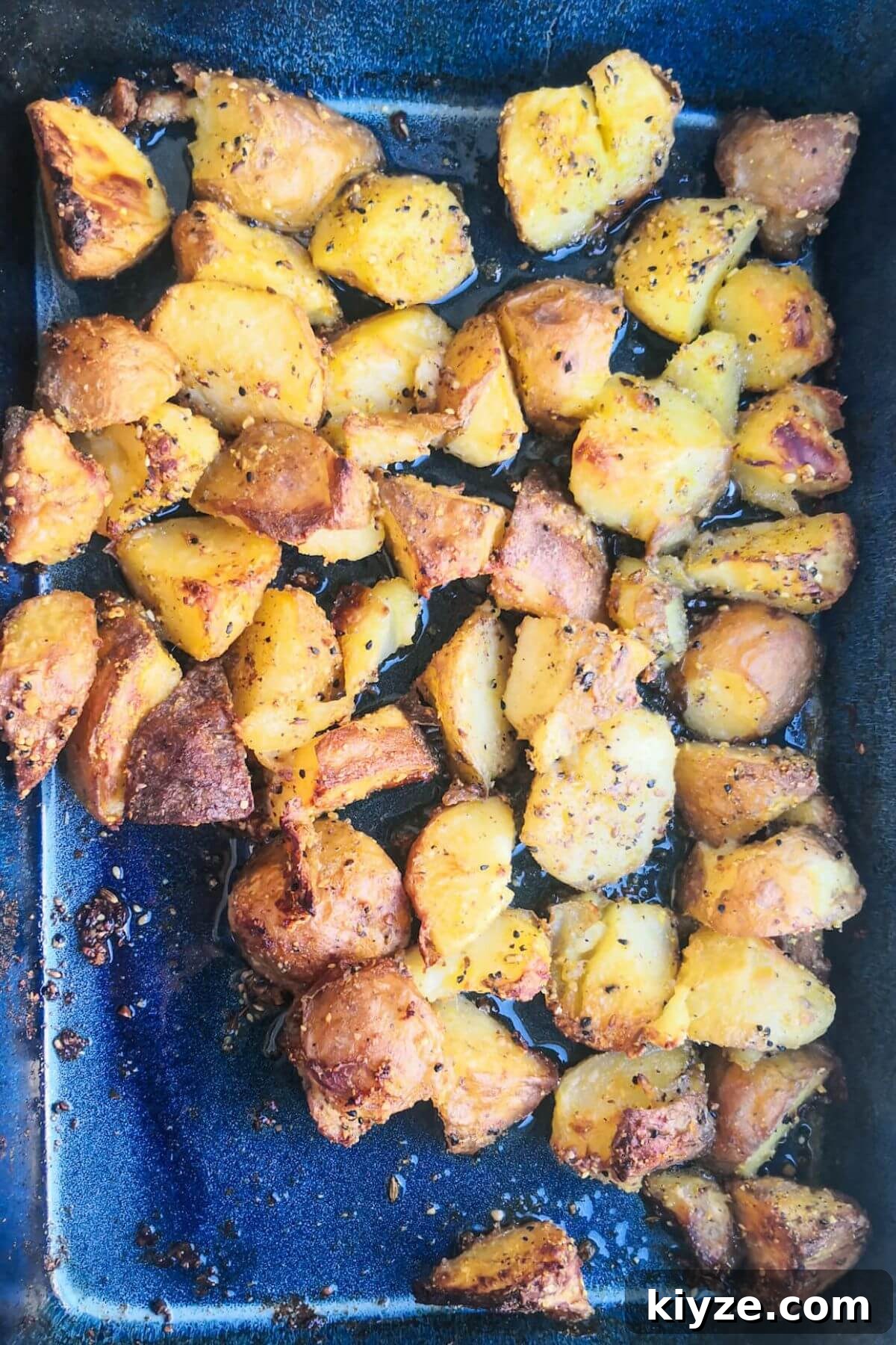 Crispy Dukkah Potatoes with Aioli & Pink Tahini Drizzle 11 Crispy dukkah potatoes after roasting in a large blue oven dish.