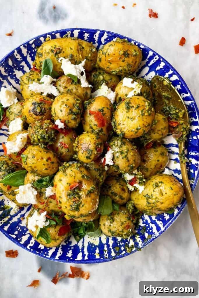 Crispy Dukkah Potatoes with Aioli & Pink Tahini Drizzle 18 Pesto potatoes with crispy prosciutto and burrata in a blue and white bowl with a gold spoon on a grey marble background.