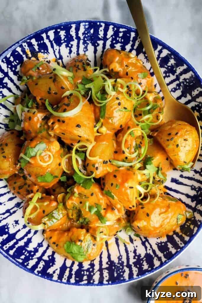 Crispy Dukkah Potatoes with Aioli & Pink Tahini Drizzle 21 Orange gochujang potatoes in a white and blue bowl with small bowl of gochujang aioli on the side.