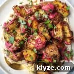 Crispy dukkah potatoes on a bed of aioli with thyme and pink tahini scattered on top.