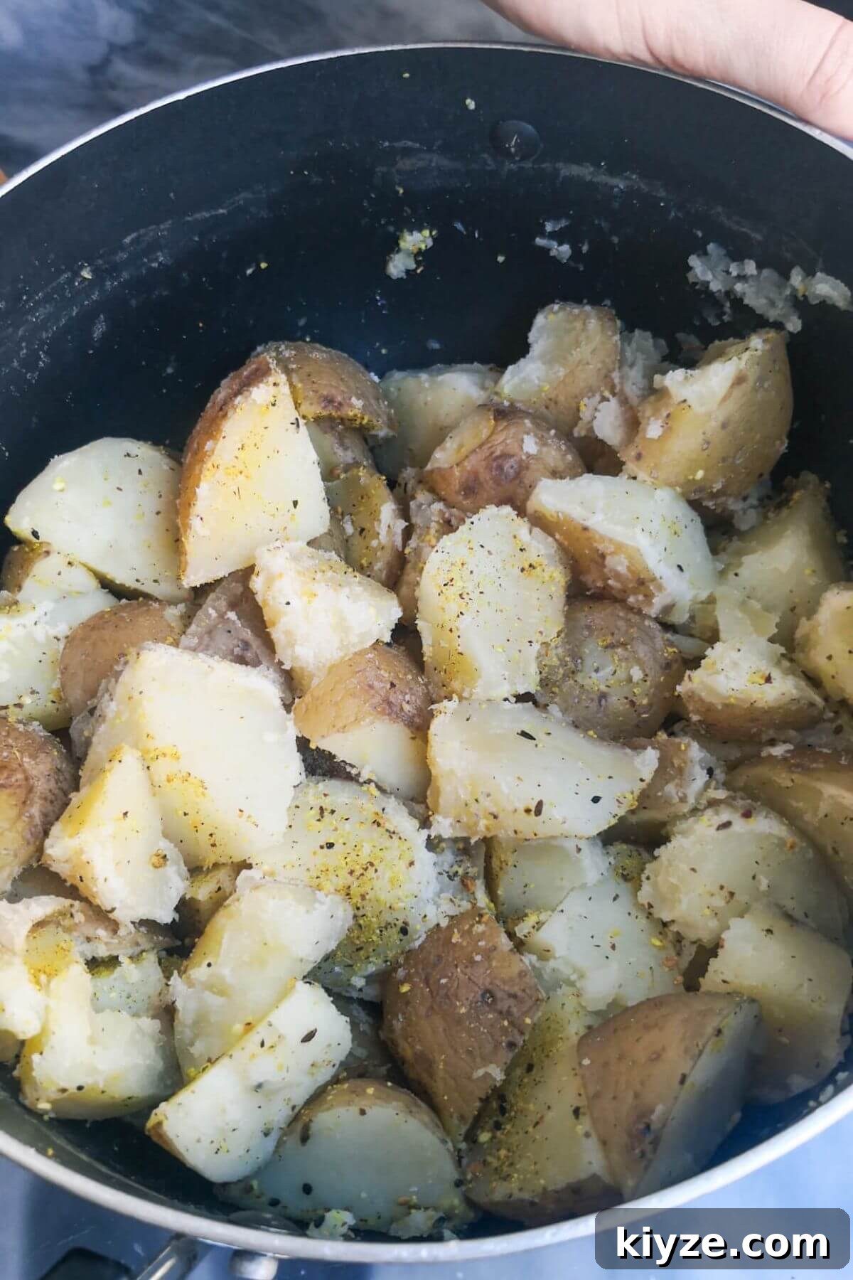 Crispy Dukkah Potatoes with Aioli & Pink Tahini Drizzle 5 Fluffed up chopped potatoes in a black pot with dukkah tossed through.