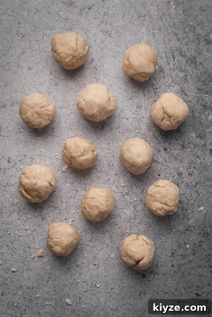 12 balls of flour tortilla dough lined up next to one another.