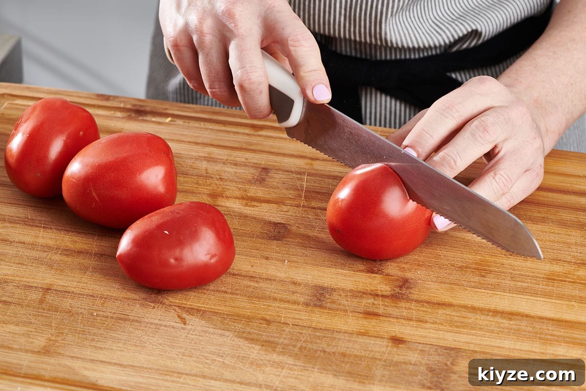 How to Slice and Dice Tomatoes Like a Pro 2 Katie Workman cutting plum tomatoes on cutting board with large knife.