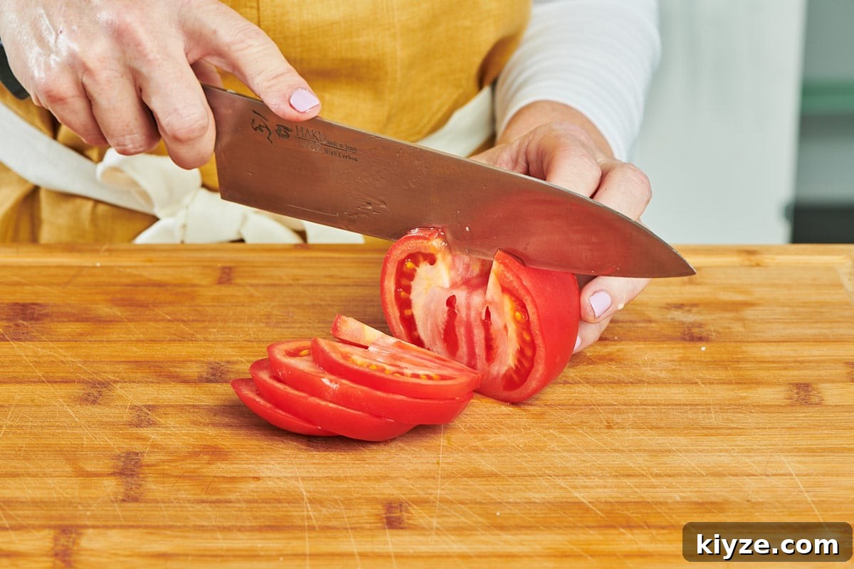 How to Slice and Dice Tomatoes Like a Pro 5 Katie Workman slicing large red tomato on cutting board with chef's knife.