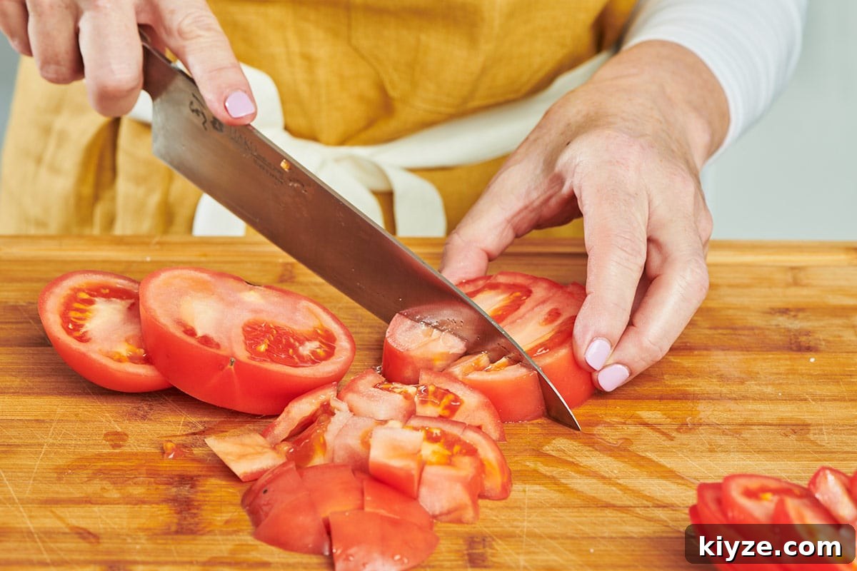 How to Slice and Dice Tomatoes Like a Pro 6 Katie Workman dicing sliced tomatoes on cutting board with chef's knife.