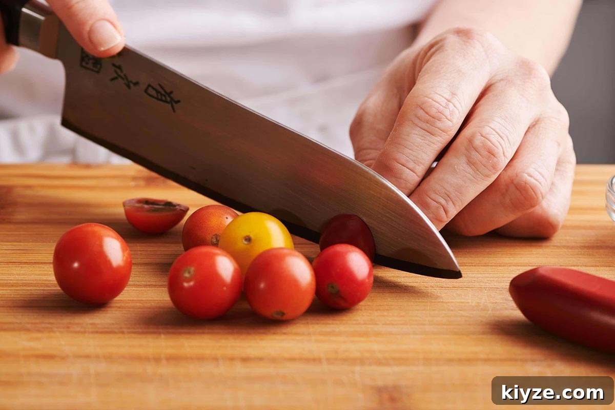How to Slice and Dice Tomatoes Like a Pro 7 Slicing cherry tomatoes with large chefs knife on wood cutting board.