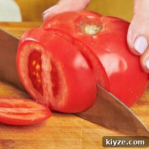 How to Slice and Dice Tomatoes Like a Pro 8 Katie Workman slicing large tomato with chef's knife on cutting board.