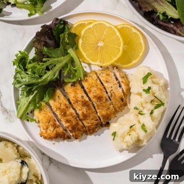 A plate of chicken cutlets with mashed potatoes and lemons.