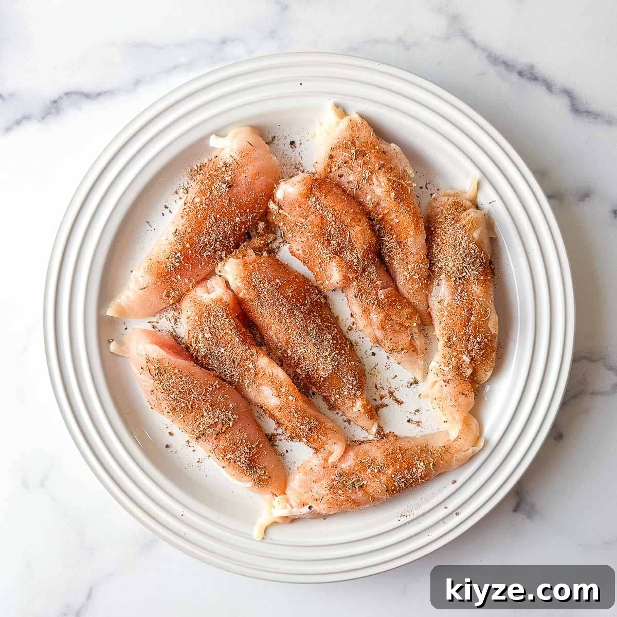 Cajun Blackened Chicken Tenders with Zesty Dipping Sauce 6 Chicken tenders on a white plate with blackened seasoning.