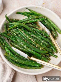 white bowl with lemon butter green beans and white tongs