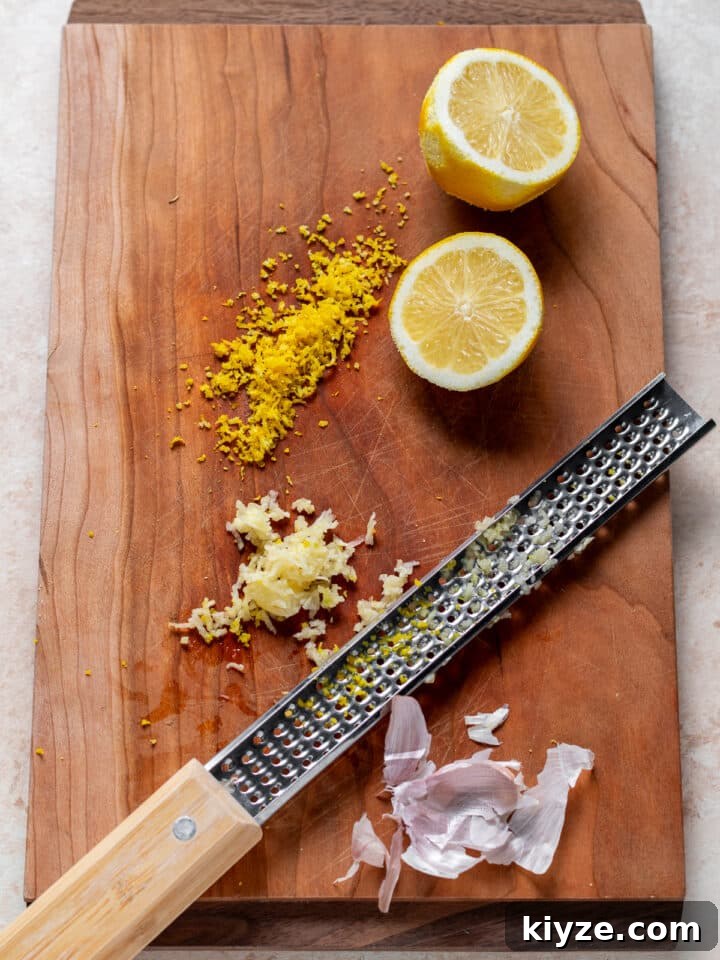 wood cutting board with lemon zest, minced garlic and a microplane