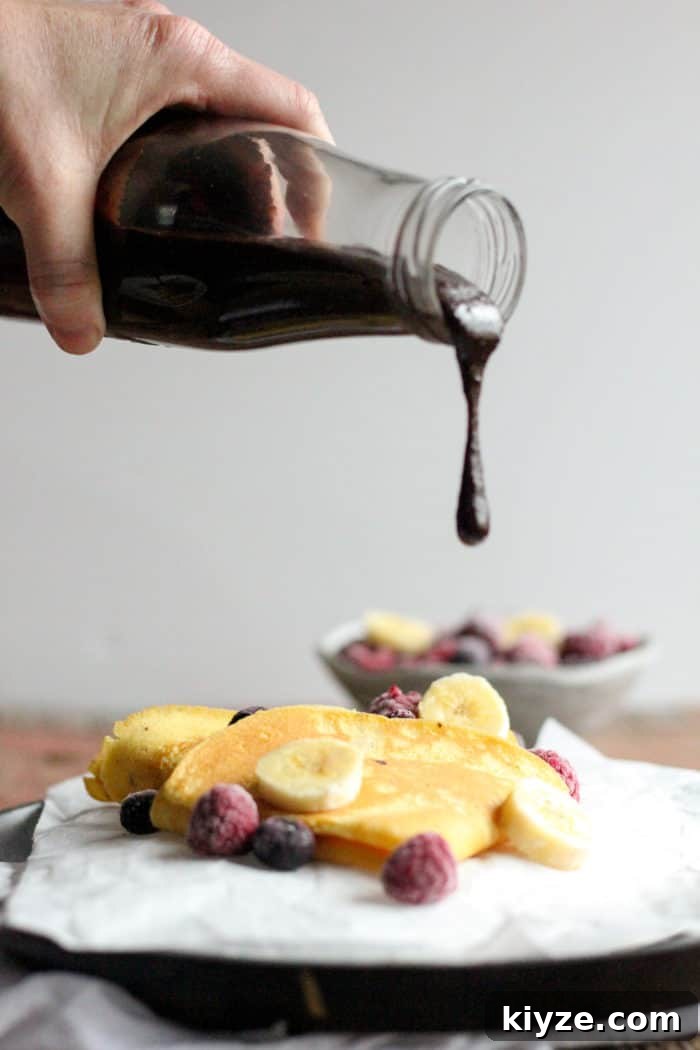 Gluten-Free Coconut Flour Crepes Recipe 3 Photo shows a plate of crepes with a bottle of chocolate sauce being poured onto them