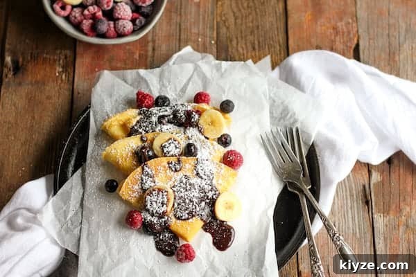 Gluten-Free Coconut Flour Crepes Recipe 7 Photo shows a plate of crepes drizzled in chocolate and berries