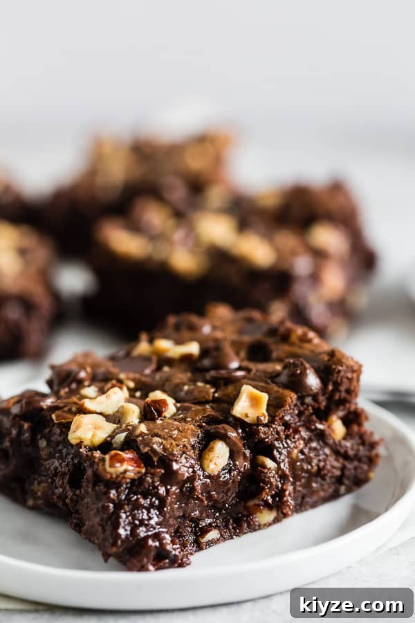Hazelnut Buckwheat Brownies Recipe with Crispy Edges 3 A cut Hazelnut Buckwheat Brownie on a small white plate.