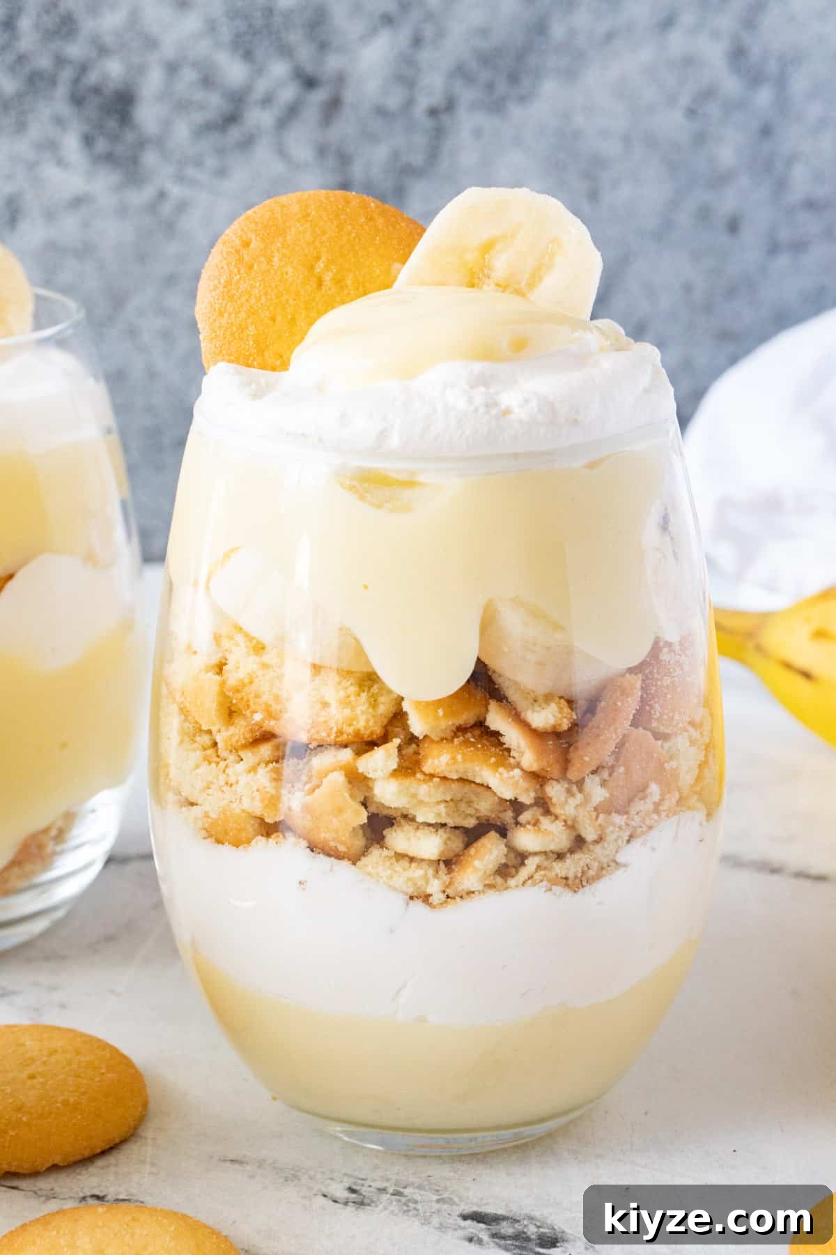 Layered pudding, sliced bananas, crushed cookies, and Cool Whip in a cup. Garnished with a banana slice and a Nilla wafer.