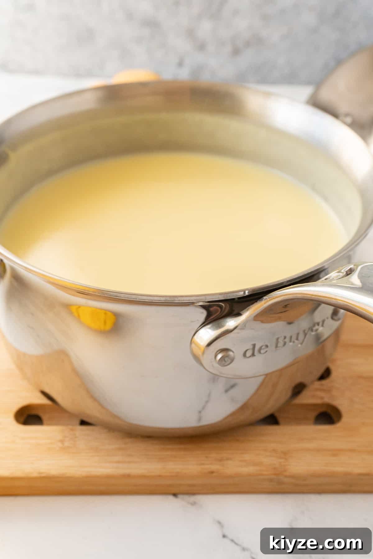 Whisked pudding in a metal saucepan on a wooden trivet.