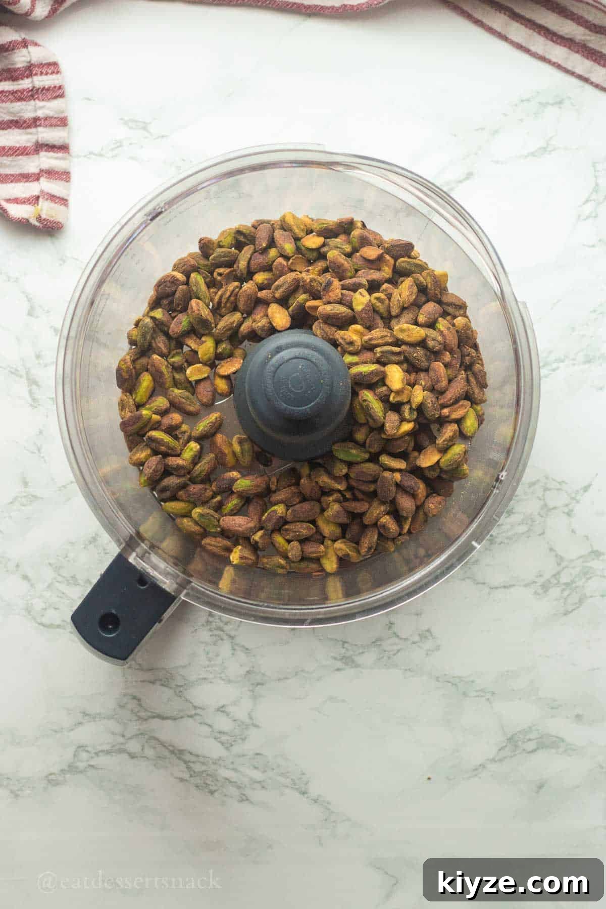 Pistachios in bowl of food processor.