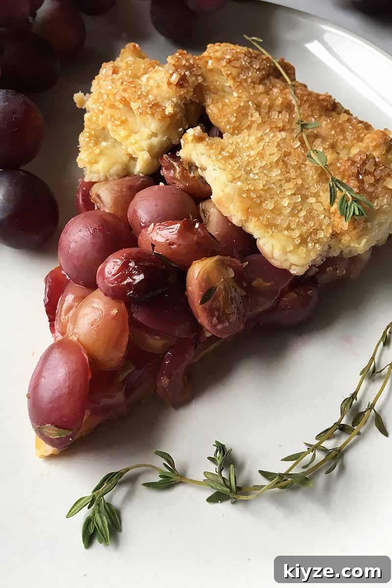 Grape Galette: Turn Fresh Grapes into a Rustic Dessert 5 Vertical image of a slice of grape galette with fresh thyme.
