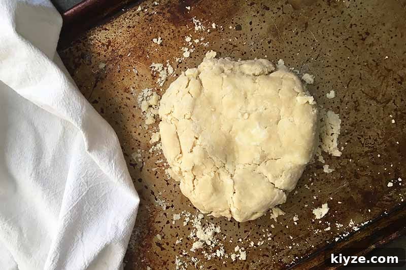 Grape Galette: Turn Fresh Grapes into a Rustic Dessert 9 Horizontal image of pie dough on a sheet pan next to a white towel.