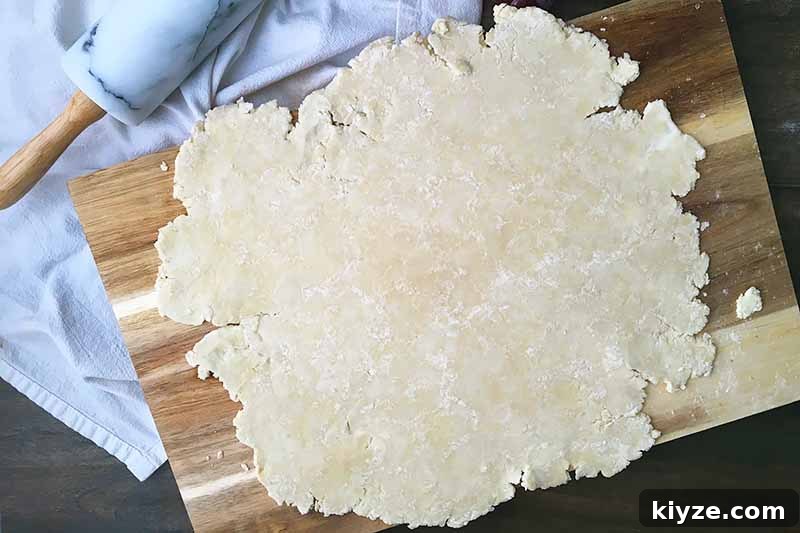 Grape Galette: Turn Fresh Grapes into a Rustic Dessert 10 Horizontal image of a rolled out pie dough on a wooden cutting board.