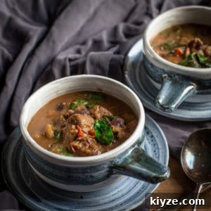 Caribbean Pepperpot Stew Made in the Slow Cooker 5 Slow cooker pepperpot stew served in two blue and white serving bowls on plates with a spoon beside them