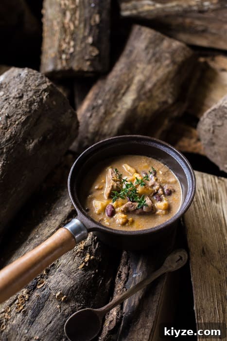 Caribbean Pepperpot Stew Made in the Slow Cooker 6 Slow Cooker Pepperpot Stew in a pan on a piece of wood with a serving spoon