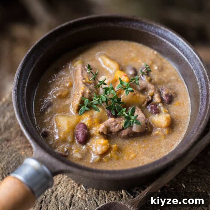 Caribbean Pepperpot Stew Made in the Slow Cooker 7 Slow Cooker Pepperpot Stew in a pan on a piece of wood with a serving spoon