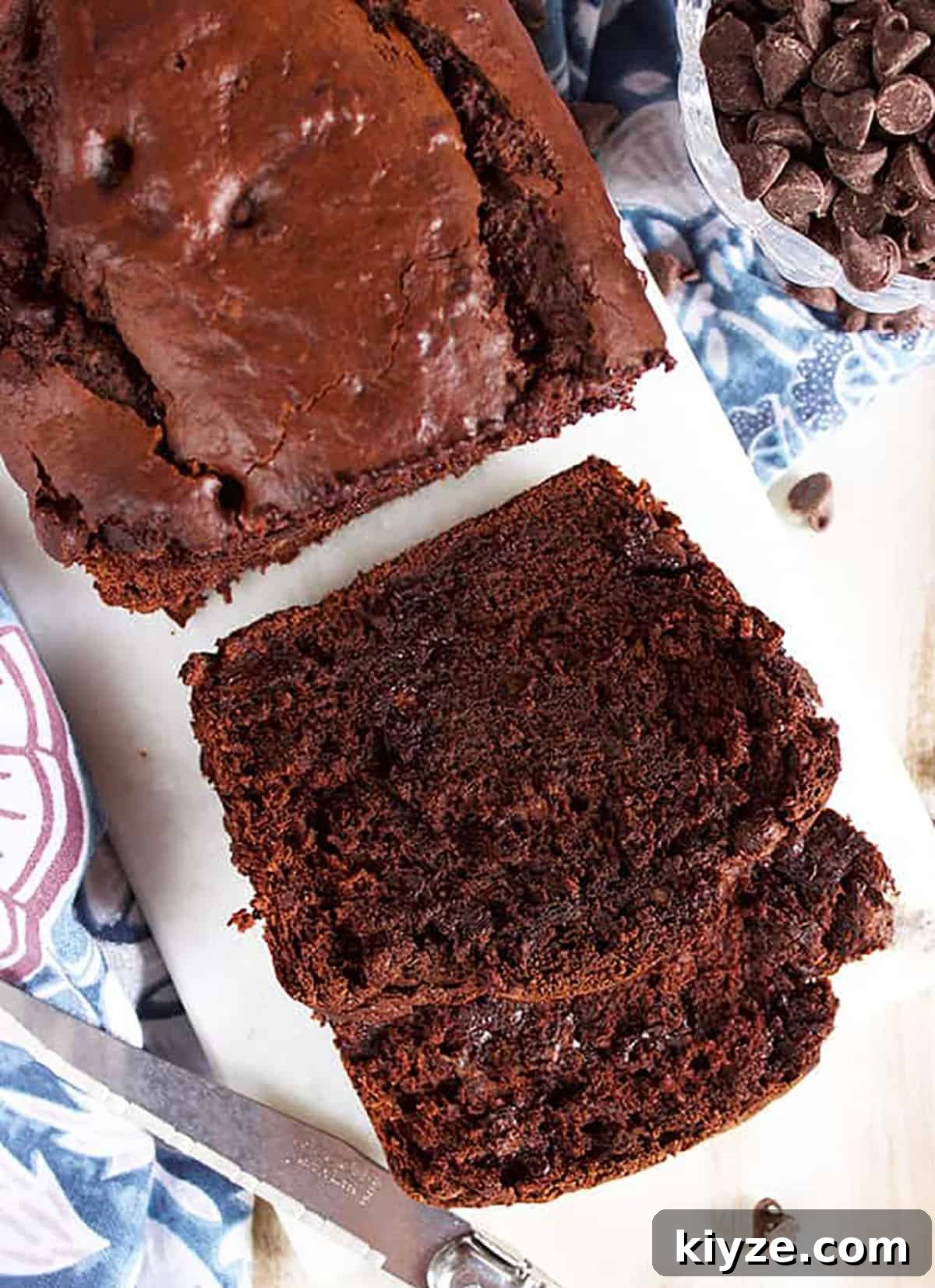 Chocolate banana bread on a marble board with two slices stacked.