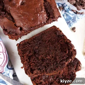 Chocolate banana bread on a marble board with two slices stacked.