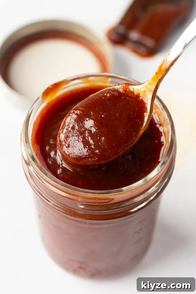 20-Minute Apricot Barbecue Sauce with Sweet and Tangy Flavor 2 Close up of apricot bbq sauce in a small mason jar with a spoon in it.