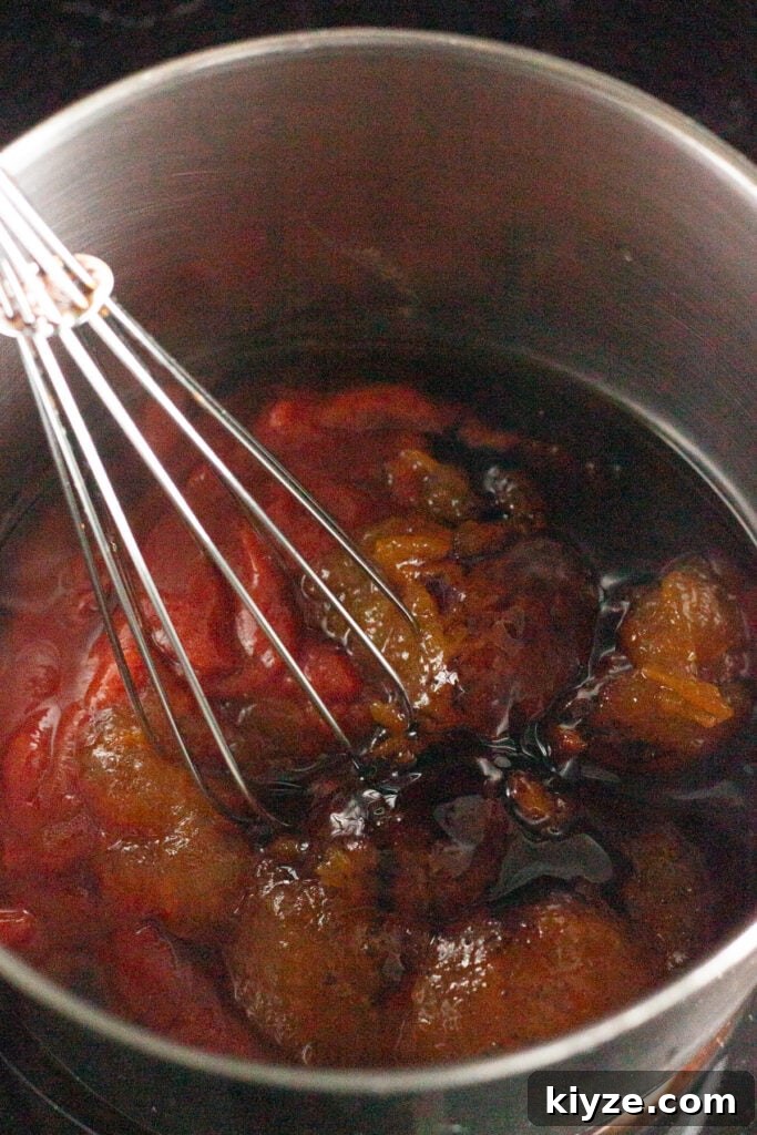 20-Minute Apricot Barbecue Sauce with Sweet and Tangy Flavor 4 A close up of a pan with ingredients for apricot bbq sauce in it, with a whisk about to stir them together.