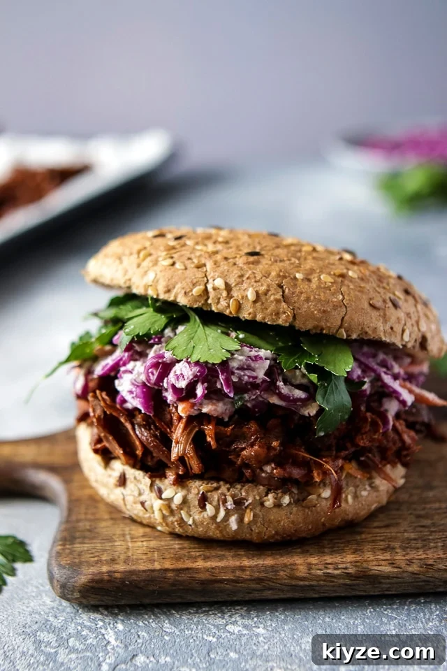 Mouthwatering vegan jackfruit sandwich on a wooden board with some green herbs to the left