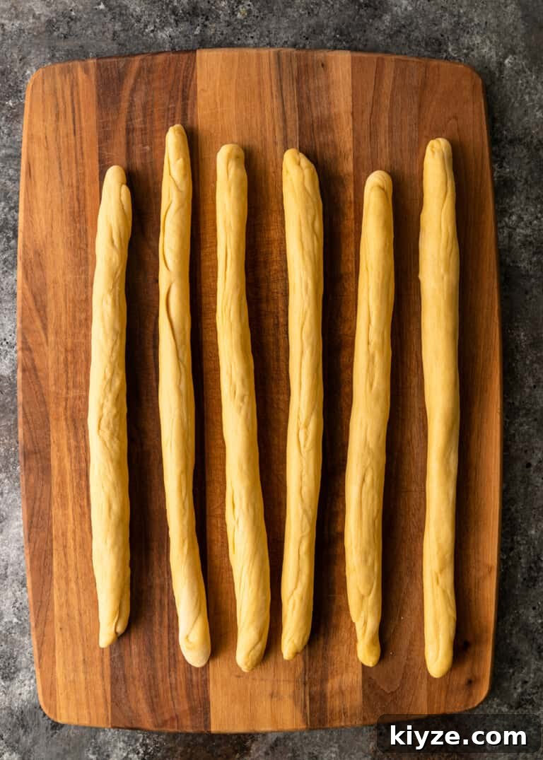 Classic Fluffy Challah Recipe for Braiding and Baking 9 dough rolled out to 6 18-inch ropes on cutting board